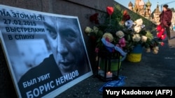 A woman passes by floral tributes at the site where opposition leader Boris Nemtsov was fatally shot on a bridge near the Kremlin in Moscow.