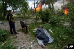 A man lies on the ground as he watches his burning house, which was destroyed by a Russian air strike, in Vovchansk, Ukraine, on May 11.