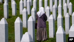 A woman walks among the graves of victims of the Srebrenica massacre at the memorial cemetery in Potocari, near Srebrenica.