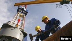 Workers prepare equipment on the drilling tower of the Shakhrinav-1P exploratory well at the Sarikamysh gas field in Tajikistan.