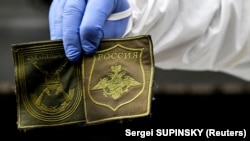 A Ukrainian forensic expert shows patches found on the body of a Russian soldier exhumed in the village of Zavalivka, west of Kyiv, on May 11.