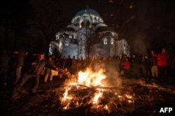 People attend a ceremonial burning of badnjak on Christmas Eve in front of St. Sava's cathedral.