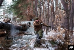 A disabled soldier with Ukraine's 127th Brigade who lost a leg in combat in 2015 takes the camouflage off his self-propelled howitzer on February 10.