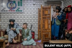 A man accused of robbery sits next to Taliban members while in custody at a police station in Kabul on September 30.