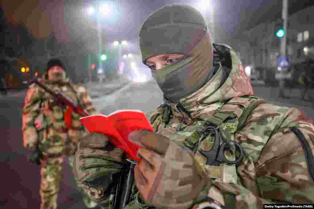 A Russian soldier checks an ID during a nighttime patrol in the occupied Ukrainian city of Makiyivka.&nbsp;