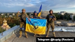 Ukrainian soldiers hold a flag atop a building in Kupyansk, in the Kharkiv region, on September 10.