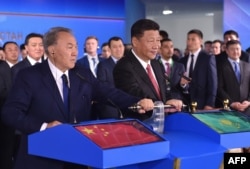 Chinese President Xi Jinping (right) and his then-Kazakh counterpart, Nursultan Nazarbaev, turn on a symbolic lever during an opening ceremony for a new train container service between western China and Western Europe in Astana on June 8, 2017.