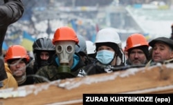 Protesters stand on a barricade built to block the way to Independence Square on December 9.