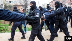 Kosovo police escort Serbian official Marko Djuric (with tie) to a police station in Pristina on March 26.