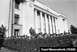 Ukrainian police stand guard outside the parliament as the protests enter their endgame.