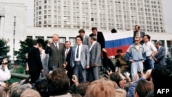 Russian President Boris Yeltsin (left) stands on top of an armored vehicle parked in front of the Russian Federation building in Moscow on August 19, 1991.