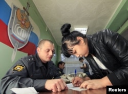 A detained illegal migrant from Central Asia fills out forms at a police station in Russia's Siberian city of Krasnoyarsk before her deportation. (file photo)