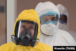 Russian President Vladimir Putin, wearing protective gear, visits a hospital for COVID-19 patients on the outskirts of Moscow on March 24, 2020.