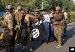 A member of the former Afghan government's security forces holds the Islamic State group's flag after an attack in Jalalabad in August 2020.