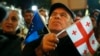 A demonstrator holds an EU and a Georgian national flag at an opposition protest against the results of the parliamentary election in Tbilisi on October 28.