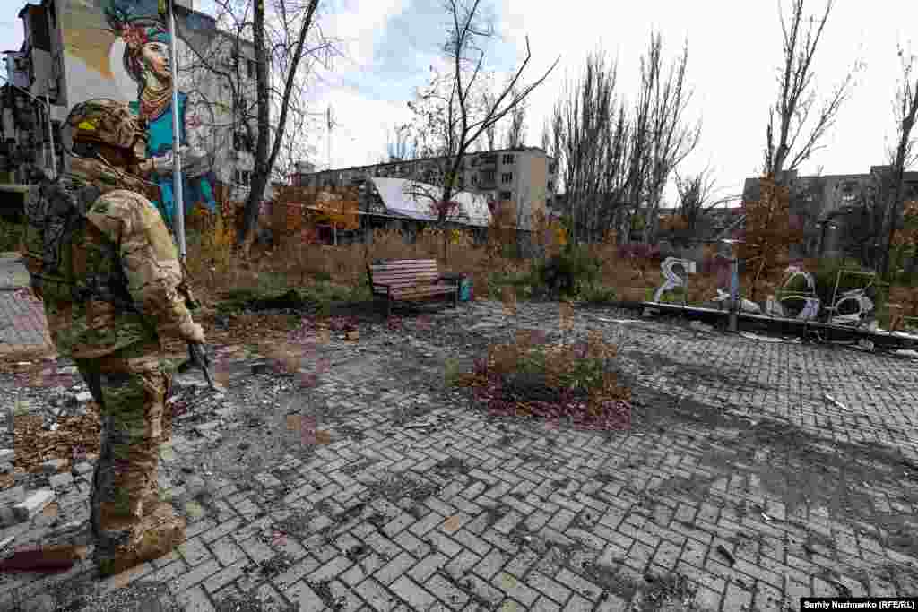 A Ukrainian soldier in Avdiyivka stands near the damaged steelwork of an "I Love Avdiyivka" sign in November 2023, when RFE/RL photojournalist Serhiy Nuzhnenko visited for the last time before the occupation of the city. The Russian Army captured Avdiyivka in February 2024, the final stage of the battle lasting more than five months.