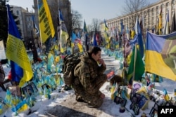 As politicians and diplomats meet, a personal moment: a soldier kneels down at a makeshift memorial for Ukrainian and foreign fighters at Independence Square in Kyiv.