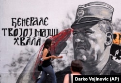 In this image from July 24, a woman walks past Mladic's "bloodied hands."