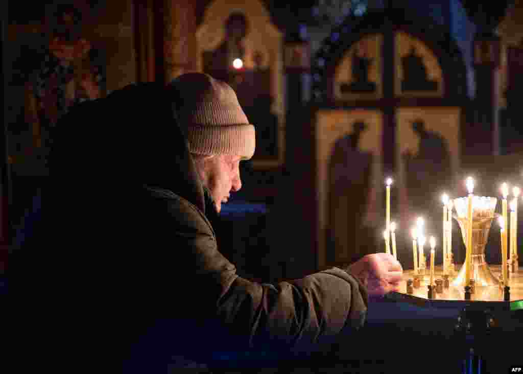 A woman lights a candle during an early celebration of the Orthodox Epiphany in a church in the Ukrainian frontline town of Lyman.&nbsp;