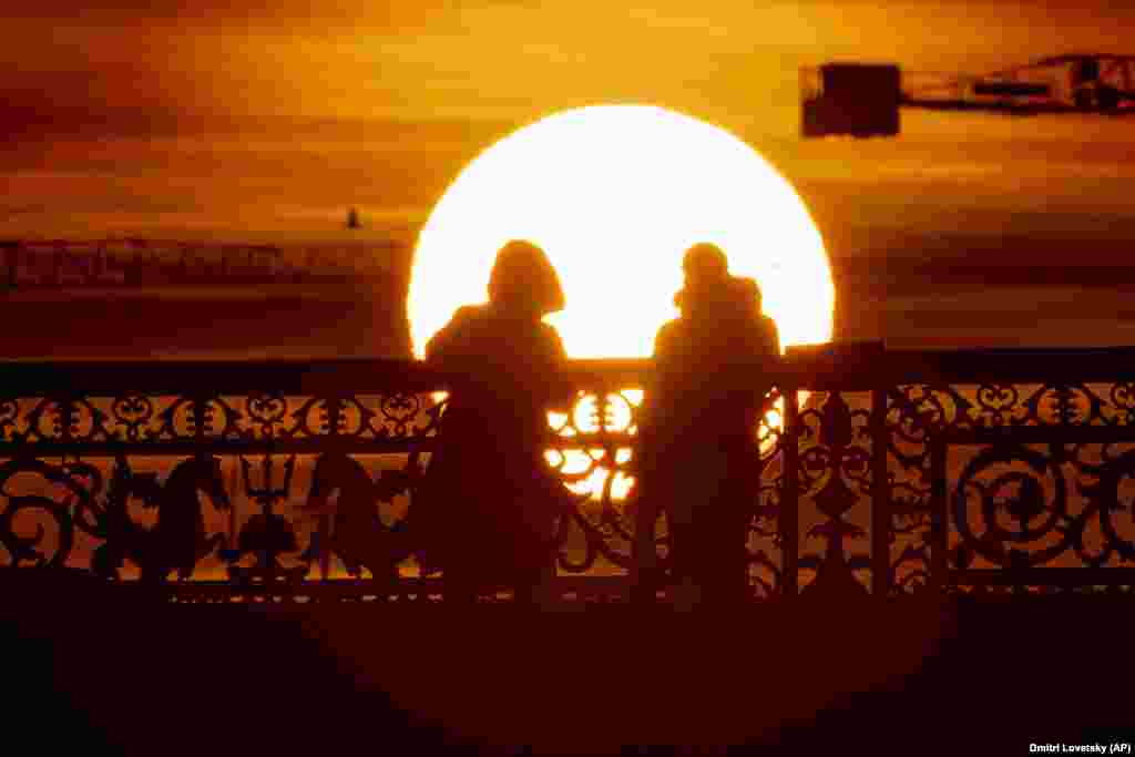 A couple stand on a bridge during sunset in St. Petersburg, Russia