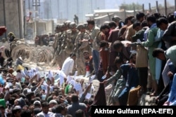 Afghans trying to evacuate the country try to show their documents to foreign forces on August 26, 2021, the day of a deadly terrorist bombing at Kabul Airport.