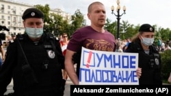 Russian police detain an opposition activist who is holding a poster reading "Smart Voting" in Moscow on August 14.