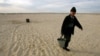 A Kazakh villager carries a bucket of water from a well in a desert that once formed the bed of the Aral Sea. (file photo)