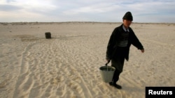 A Kazakh villager carries a bucket of water from a well in a desert that once formed the bed of the Aral Sea. (file photo)