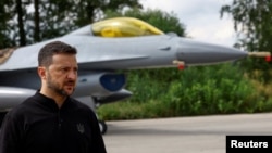 Ukraine's President Volodymyr Zelenskiy speaks to the media in a front of an F-16 after marking the Day of the Ukrainian Air Forces at an undisclosed location in Ukraine on August 4.
