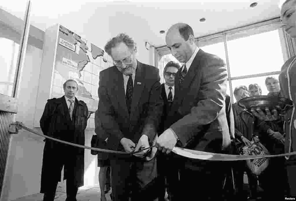 Putin (left), chairman of St. Petersburg&#39;s External Relations Committee, takes part in a ceremony to open an electronics store in St. Petersburg on April 29, 1993.