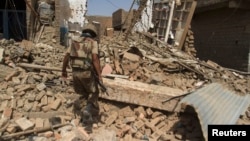 In the town of Miran Shah, North Waziristan, a Pakistani soldier inspects the site of a house destroyed during a military operation against Taliban militants in 2014.