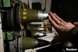 A Ukrainian serviceman touches a 155 mm shell in a self-propelled howitzer barrel near the devastated Ukrainian city of Bakhmut on January 16.