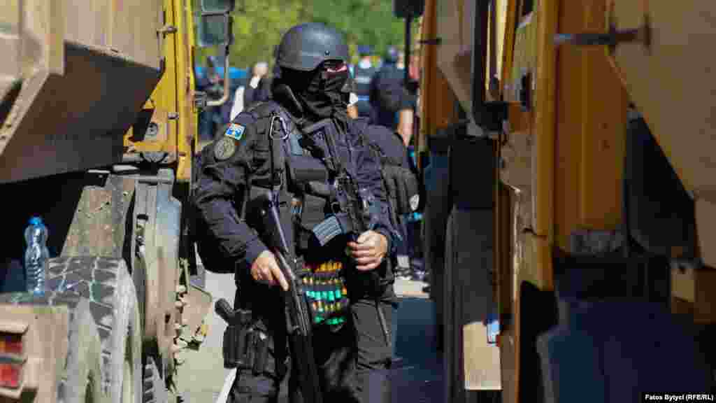 A Kosovar police officer stands next to trucks blocking the road in Jarinje.