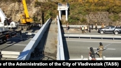 Emergency service workers at the site of a collapsed pedestrian bridge over a motorway in Vladivostok on October 16.