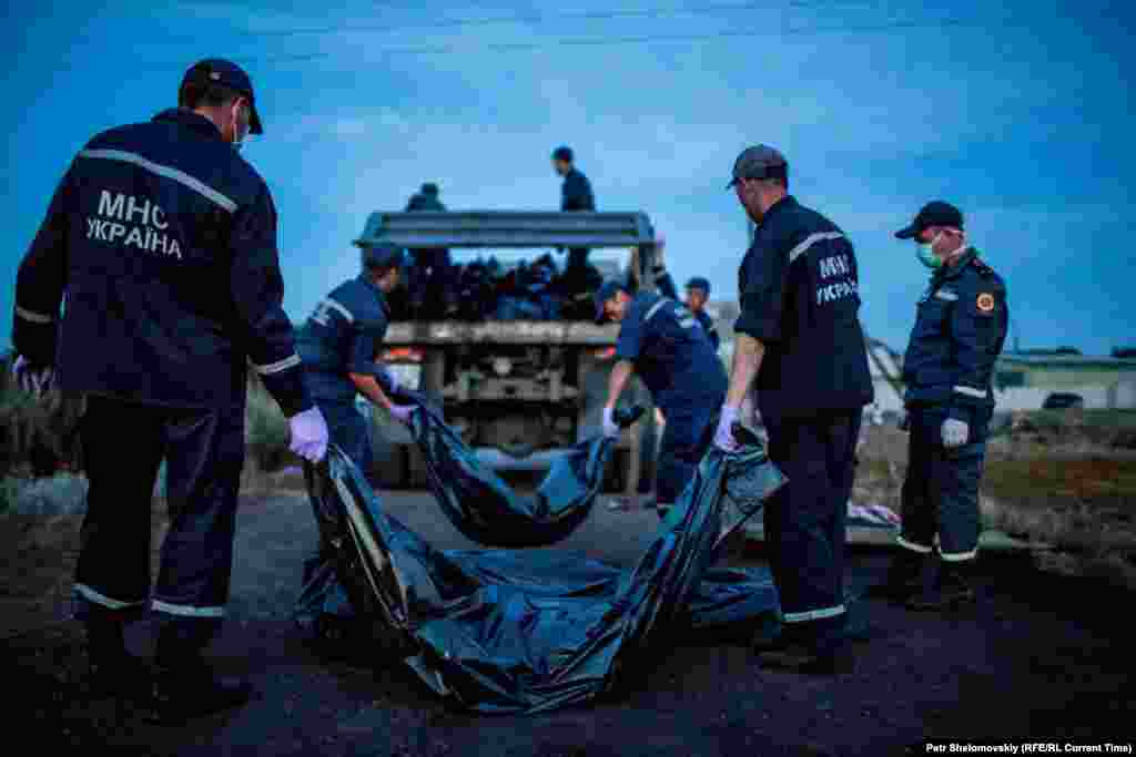 Shortly after the disaster, rescue workers carry body bags containing the remains of passengers and crew from flight MH17.