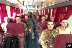 In a photo taken from video released by the Russian Defense Ministry, a group of Russian soldiers captured in the Kursk region ride on a bus after being released in a swap between Russia and Ukraine, at an unspecified location, on September 14, 2024.