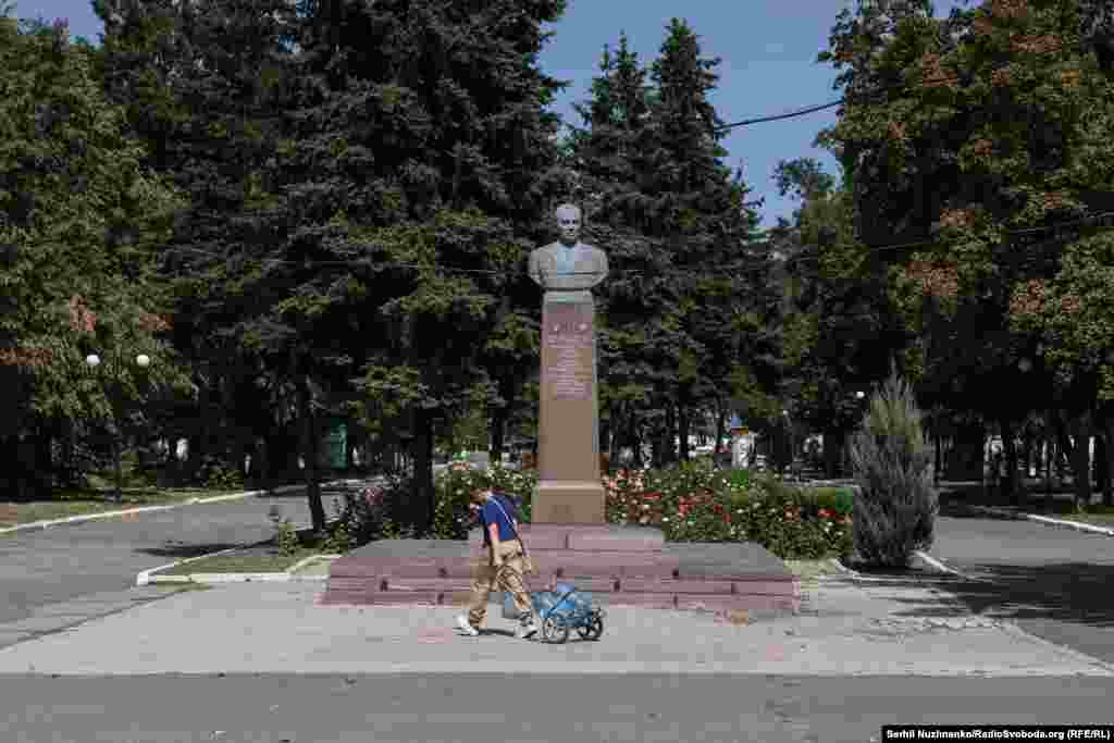 A teenager pulls a &quot;crawler&quot; filled with big water bottles past a monument to a Hero of the Soviet Union, Kirill Moskalenko, who was born nearby.