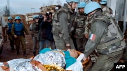 UN personnel carry away a victim of the Markale market attack in Sarajevo on February 6, 1994. 