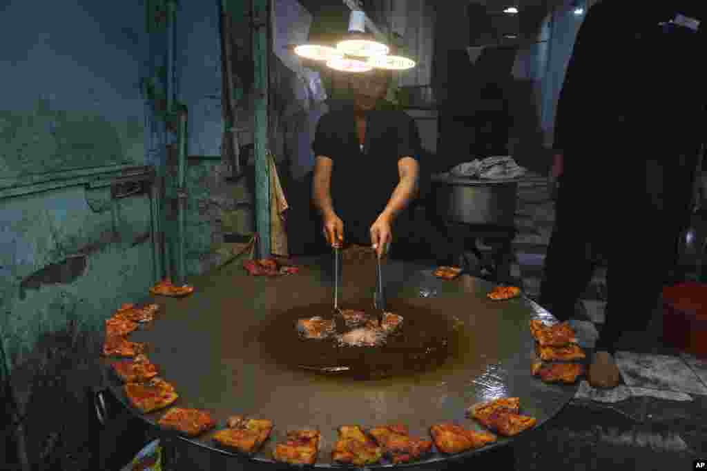 A worker fries fish for customers at a restaurant, in Peshawar, Pakistan.