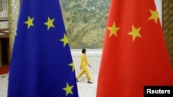 An attendant walks past EU and China flags ahead of the EU-China High-level Economic Dialogue in Beijing in 2020. 