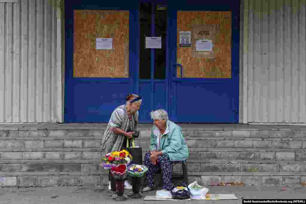 Women sell flowers and vegetables near a closed supermarket. In Pokrovsk, all large supermarkets and shopping centers are closed. Only small grocery stores remain open.