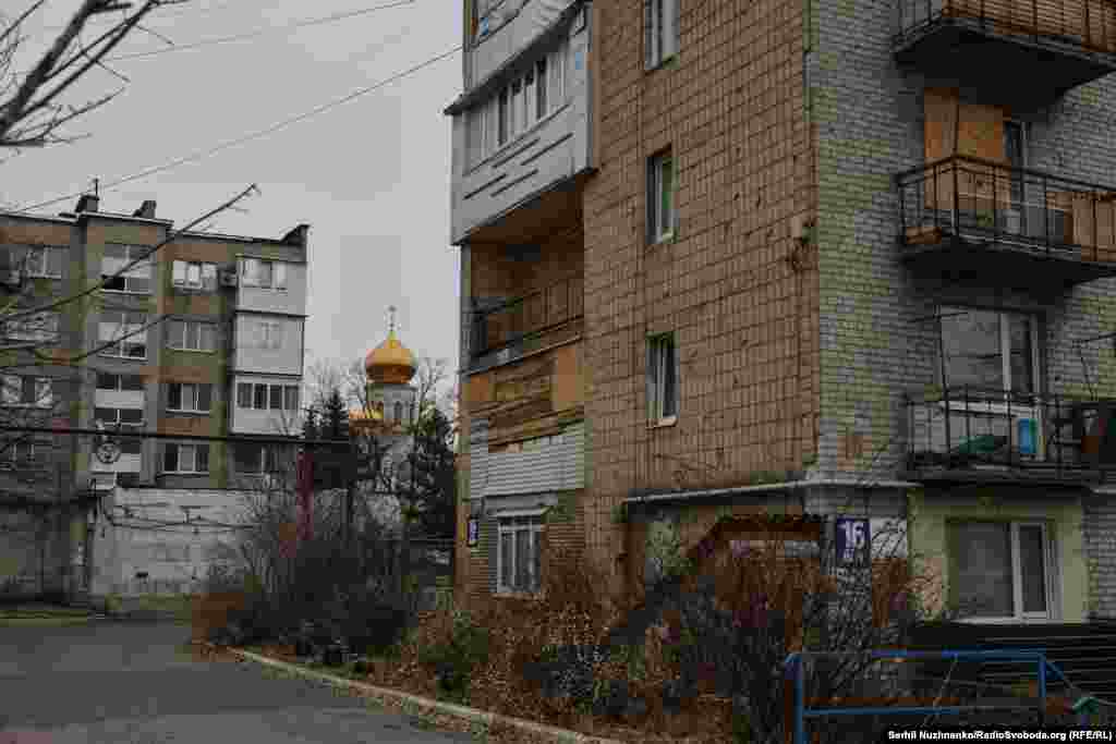 Bells in the cathedral begin to ring, calling the faithful to prayer and momentarily drowning out the sounds of war. The bells frighten a flock of pigeons which flap into the air then settle on the Soviet-era apartment block whose windows are boarded up with chipboard.