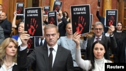 Opposition deputies hold signs reading "You have blood on your hands" during a session of the Serbian parliament in Belgrade on November 25.