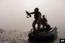 A Ukrainian soldier jumps out of a boat onto the shore of the Dnieper River at the front line near Kherson on October 15.