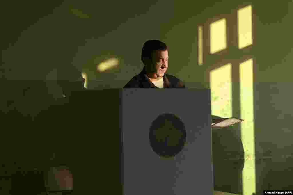 A Kosovar man prepares his ballot in the booth to vote in the parliamentary elections at a polling station in the town of Gracanica.