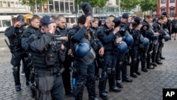 German police officers take off their caps in Mannheim after learning that an officer who was stabbed had died on June 2.