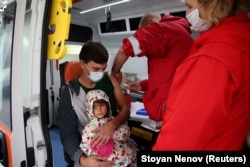 A man holds his daughter as he receives a second dose of a vaccine against COVID-19 in the Bulgarian village of Krushovitsa last month.