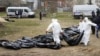 Men wearing protective gear exhume the bodies of civilians killed during the Russian occupation of Bucha, on the outskirts of Kyiv, on April 8, 2022.