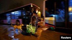 A woman rushes to board a bus arranged to evacuate local residents in the separatist-controlled city of Donetsk on February 18. "Where are we running to? Where are they taking us?" someone wrote on social media.