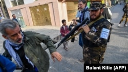 A Taliban special forces officer pushes a journalist covering a demonstration by women protesters outside a school in Kabul. (file photo)